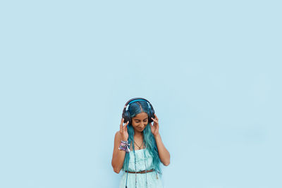 Young woman listening music against blue background