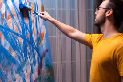 Side view of man painting at home