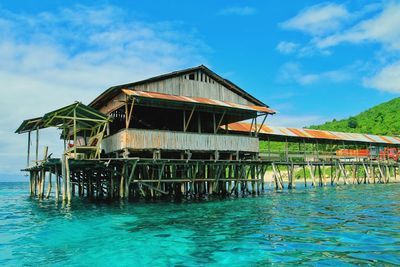 Stilt house over sea against sky