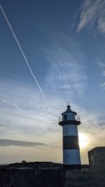 Lighthouse by sea against sky during sunset