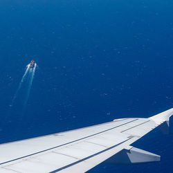 Airplane flying over sea against blue sky