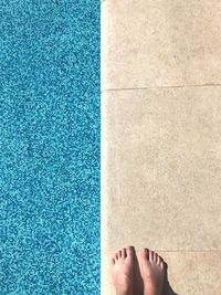 Low section of person standing by swimming pool