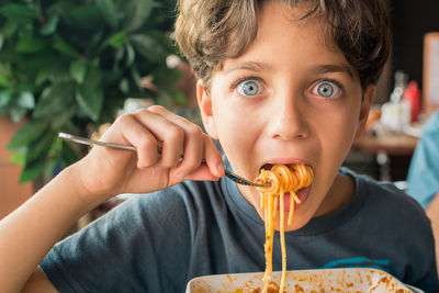 Close-up portrait of boy eating noodles