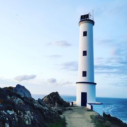 Lighthouse by sea against sky