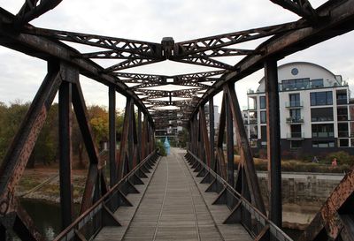 Footbridge over footpath against sky