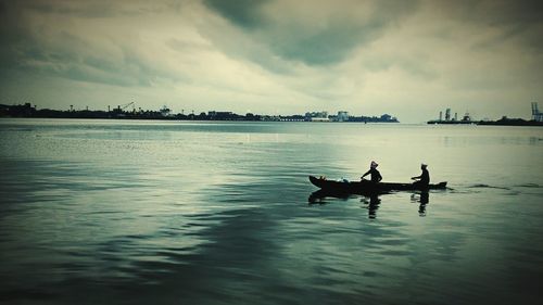 Silhouette men in sea against sky