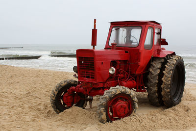 Tractor at beach against clear sky