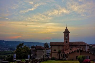 Church amidst buildings against sky during sunset