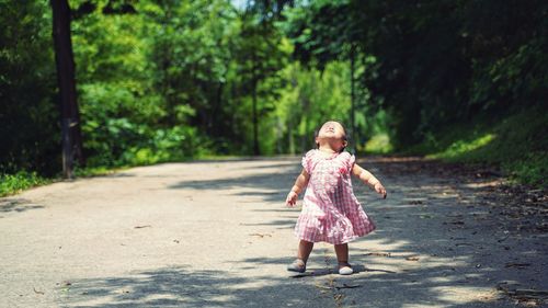 Full length of baby girl standing on road against trees