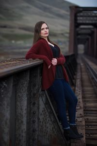 Portrait of beautiful woman leaning on railway bridge railing