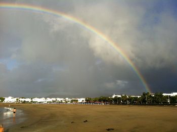 Rainbow over sea against cloudy sky