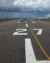 Road sign on airport runway against sky