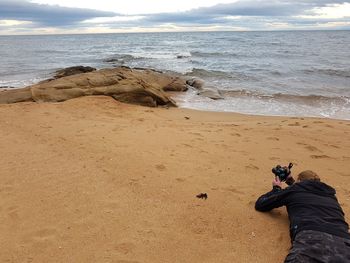 Man photographing at beach against sky