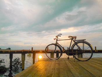 Bicycle on bridge against sky during sunset