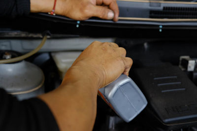 Cropped hand of man pouring oil in car