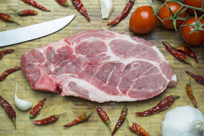 Close-up of pork steak with ingredients on cutting board