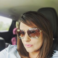 Portrait of young woman wearing sunglasses in car