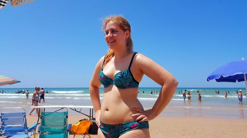 Happy friends enjoying at beach against blue sky