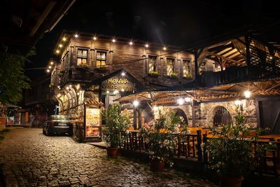 Illuminated street amidst buildings in city at night