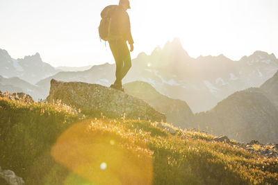 Side view of hiker backpacking across a high mountain range.