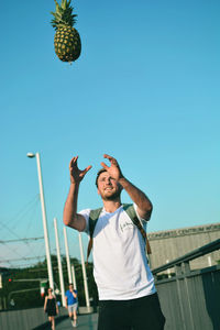 Man throwing pineapple while standing outdoors