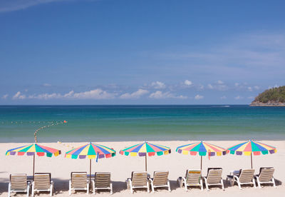 Chairs on beach by sea against sky