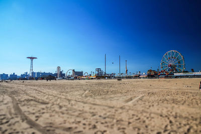 Amusement park on beach against clear blue sky