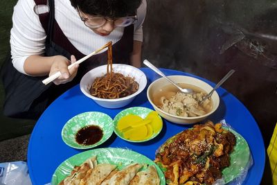 High angle view of young woman having noodles in restaurant