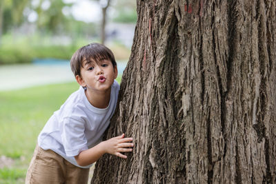 Portrait of boy standing on tree trunk