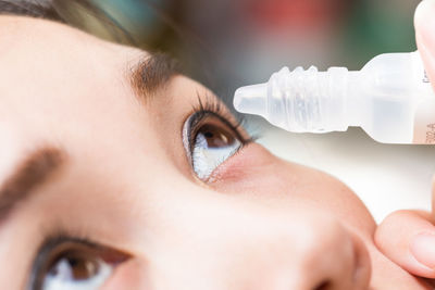 Close-up of woman putting eye drops