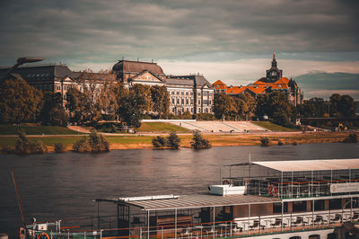 Buildings by river against sky