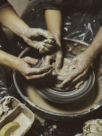 Midsection of man making pot with coworker