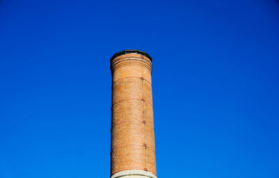 Low angle view of smoke stack against blue sky