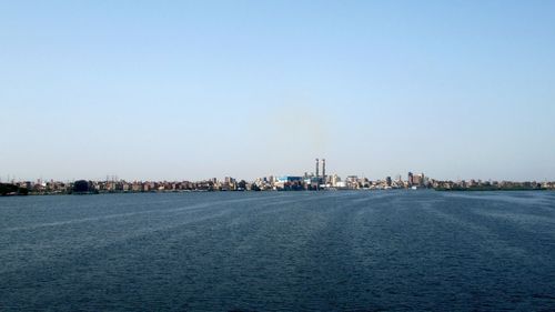Sea by buildings against clear sky
