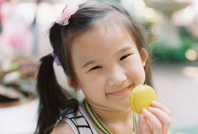 Close-up portrait of smiling girl holding macaroon