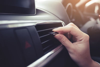 Cropped hand adjusting air conditioner in car