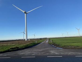 Wind turbines on field against clear sky