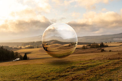 Hot air balloons on field against sky