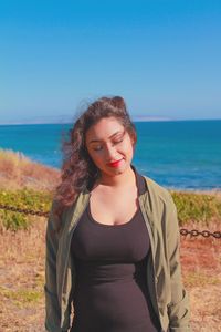 Young woman standing at beach against sky