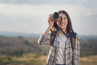 Full length of smiling woman standing against camera