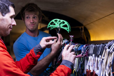 Man making funny face while trying to choose climbing gear to take