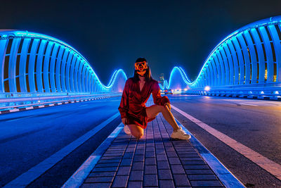 Full length of young man on illuminated road at night