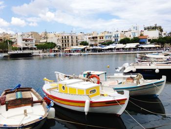 Boats moored at harbor against buildings in city
