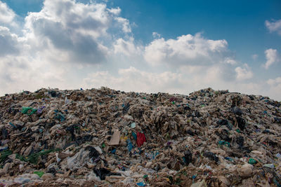 Stack of garbage on rock against sky