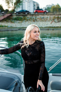 Happy beautiful young woman in black dress standing in vessel