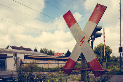 Railroad crossing sign against sky