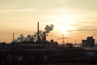Industrial building against sky during sunset