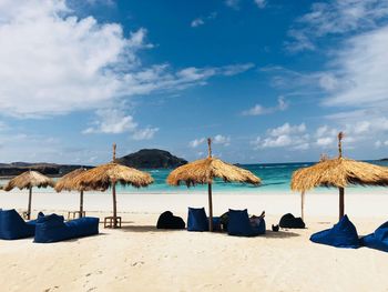 Lounge chairs and parasols on beach against sky