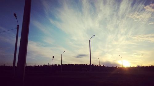 Silhouette street lights against sky during sunset