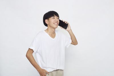 Young man looking away while standing against white background